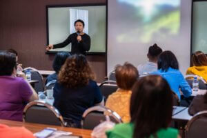 miles marketing Asian Speaker or lecture with casual suit on the stage in front of the room presenting with the screen in the conference hall or seminar meeting room business and education concept